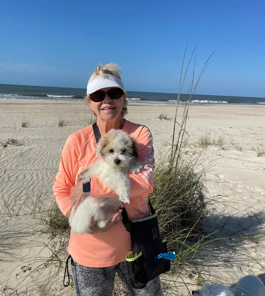 A new owner holding a puppy at the beach